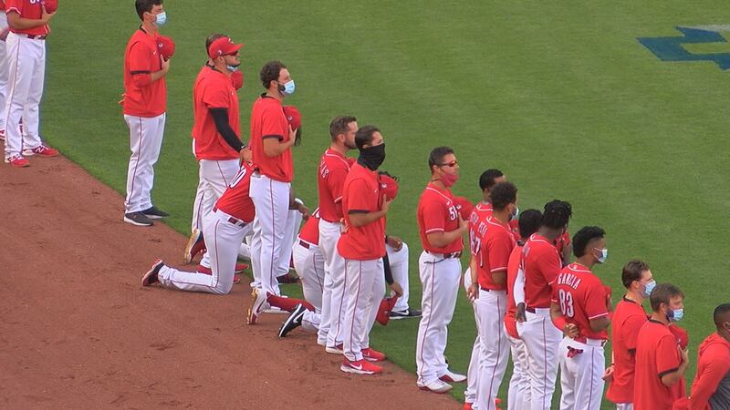 Four Reds players including Joey Votto kneel during the National Anthem.