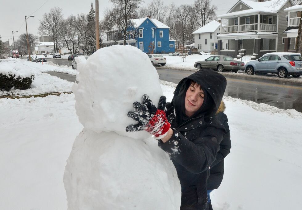 Blake Wise applies the head of the snowman that he and Brianna Atwood built along South 7th...